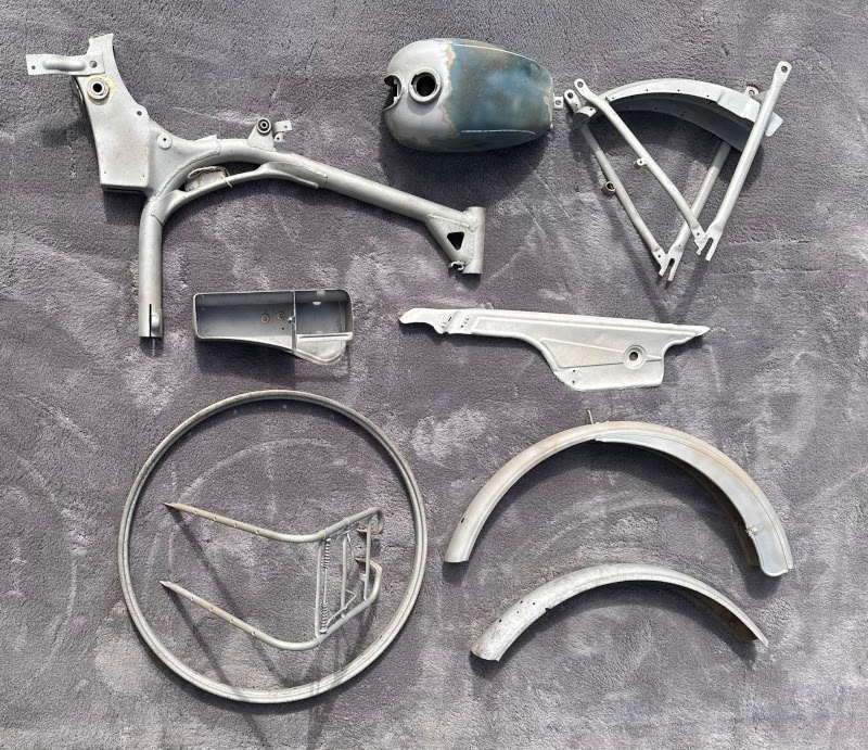 Dieselben Moped-Teile nach dem Sandstrahlen – blankes, vollständig entlacktes Metall